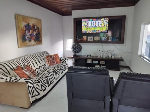 a living room with a couch and a tv at Casa com Piscina Grande em Salinas in Salinópolis