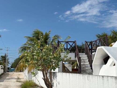 a white fence with a tree next to a building at House with Pool, Rooftop, Terrace & Bar, AC in Chuburná