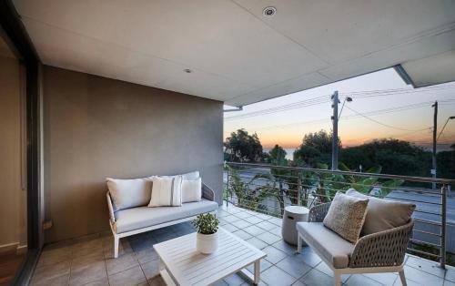 a balcony with two chairs and a couch and a table at 4 bed beachfront home in Sandringham w Spa and sunset views in Black Rock North