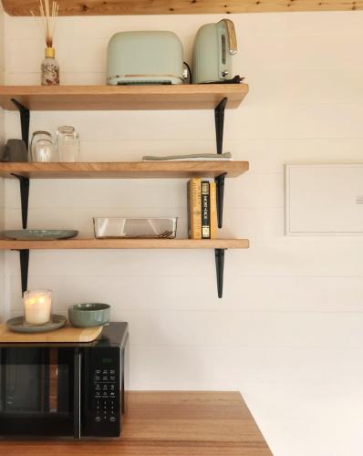 a kitchen with wooden shelves and a microwave at Bright Accommodation Park in Bright