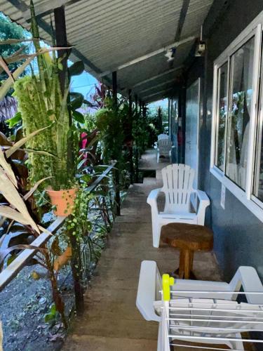 a porch with white chairs and plants on it at Apartamentos Equipados DMR #3 in Uvita