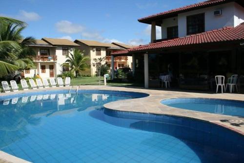 a swimming pool in front of a house at Apartamento Em frente a praia - Piscina condomínio América Praia, acesso privativo para a praia in Porto Seguro