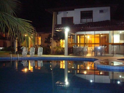 a swimming pool in front of a house at night at Apartamento Em frente a praia - Piscina condomínio América Praia, acesso privativo para a praia in Porto Seguro