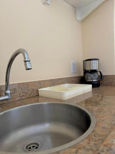 a kitchen counter with a sink and a coffee maker at Studio pé na areia, vista, internet e ar in Macaé
