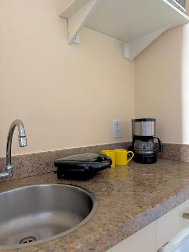 a kitchen counter with a sink and a appliance at Studio pé na areia, vista, internet e ar in Macaé