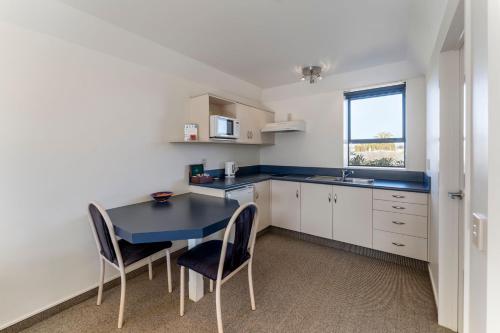 a small kitchen with a blue table and chairs at Avalon Manor Motel in Motueka