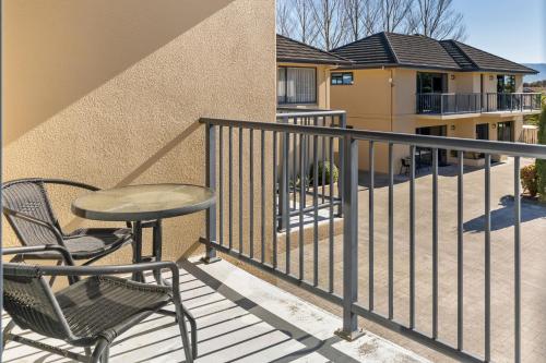a balcony with a table and chairs and a building at Avalon Manor Motel in Motueka