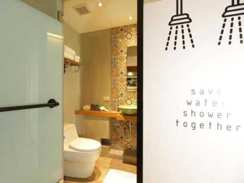 a bathroom with a toilet and two lights at Nandha Hotel in Bangkok