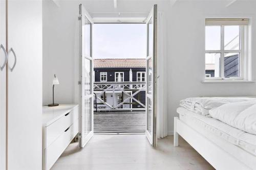 une chambre blanche avec une porte donnant sur un balcon dans l'établissement TV1274-Bindslev-Tannisbugtvej-49-D-Nr-10, à Bindslev
