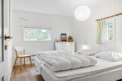 a large white bed in a white bedroom with a chair at TV1557-Albaek-Apollonvej-1 in Ålbæk