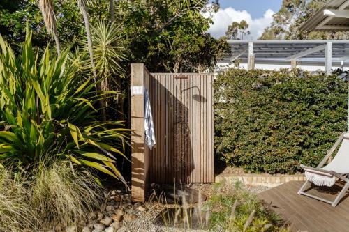 a garden with a wooden fence and a chair at Oyster Catcher Huskisson in Huskisson