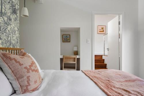 a bedroom with a white bed with a pink blanket at Oyster Catcher Huskisson in Huskisson