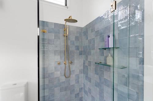 a bathroom with a shower with blue tiles at Oyster Catcher Huskisson in Huskisson