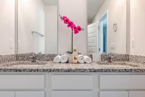 a bathroom with two sinks with towels and pink flowers at Turnkey Coastal Luxury Townhome EV Ready in Pensacola