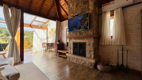 a living room with a fireplace and a tv at Pousada Villa Monte Verde in Monte Verde