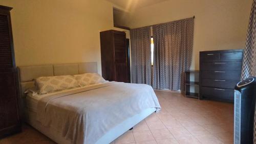 a bedroom with a white bed and a dresser at El Santuario Ecolodge in Boquete