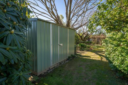 a green privacy fence in a yard with trees at Avalon Manor Motel in Motueka