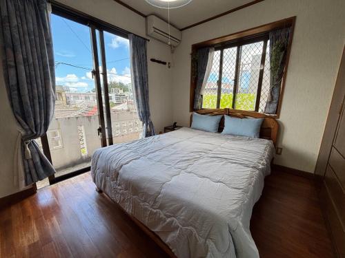 a bedroom with a large bed with a large window at 沖縄やどや in Nago