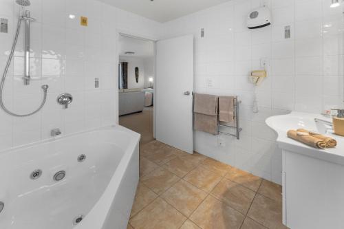 a white bathroom with a tub and a sink at Avalon Manor Motel in Motueka