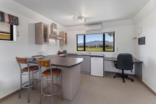 a kitchen with a counter and chairs and a window at Avalon Manor Motel in Motueka