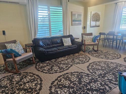 a living room with a black leather couch and chairs at Casa Verde in Naguabo