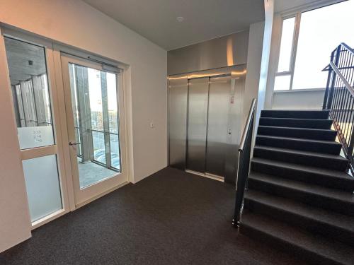 a staircase in a building with a glass door at Modern and Cozy apartment in the city next to Heiðmörk, nature reserve - Birta Rentals in Garðabær