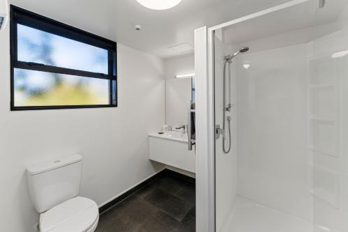 a white bathroom with a toilet and a window at Avalon Manor Motel in Motueka