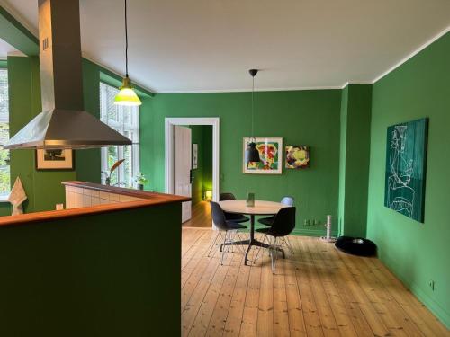 a kitchen with green walls and a table and chairs at GreenBrook Homes in Aalborg