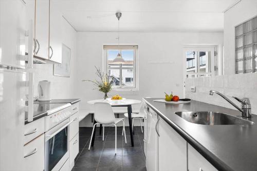 une cuisine blanche avec un évier et une table dans l'établissement TV1280-Bindslev-Tannisbugtvej-49-D-Nr-5, à Bindslev
