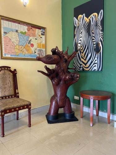 a statue of a tree next to a chair and two zebras at Okera Inn Hotel in Accra