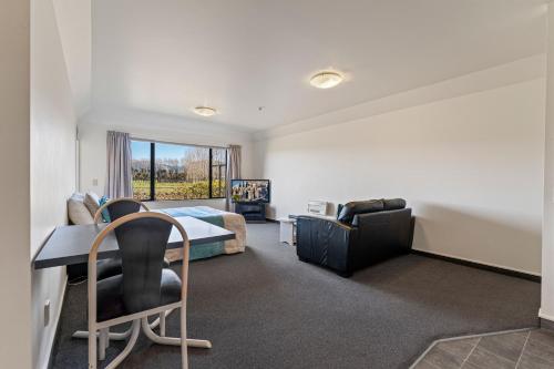 a bedroom with a bed and a desk and chairs at Avalon Manor Motel in Motueka