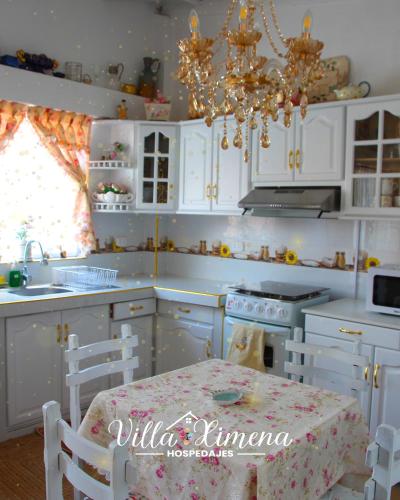 eine Küche mit weißen Schränken, einem Tisch und einem Kronleuchter in der Unterkunft Villa Ximena in Puno