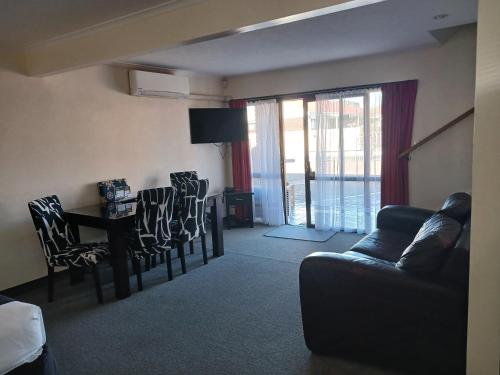 a living room with a couch and a table and chairs at Palm City Motor Inn in Napier