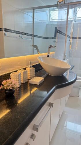 La salle de bains est pourvue d'un lavabo sur un comptoir noir. dans l'établissement Apartamento Lindo com sacada vista mar! Pé na areia!!!, à Guarujá