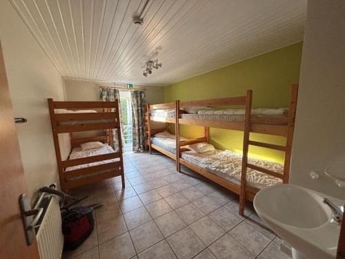 a room with three bunk beds and a sink at Holiday Home in Robertville with Sauna & Garden in Robertville
