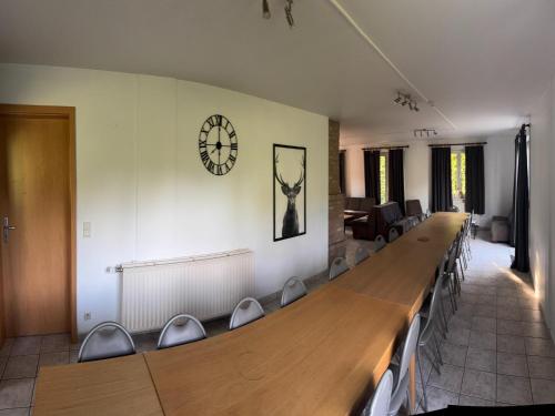 a conference room with a long desk and a clock on the wall at Holiday Home in Robertville with Sauna & Garden in Robertville