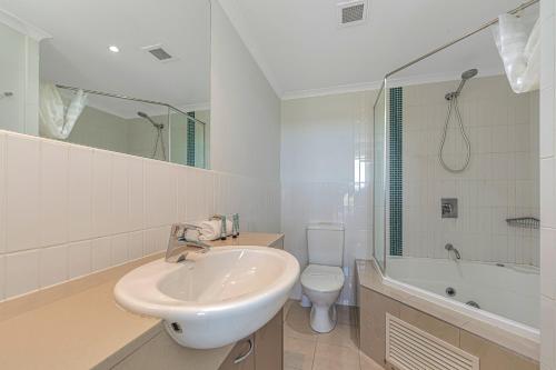 a white bathroom with a sink and a toilet at Ettalong Beach Luxury Apartments in Ettalong Beach