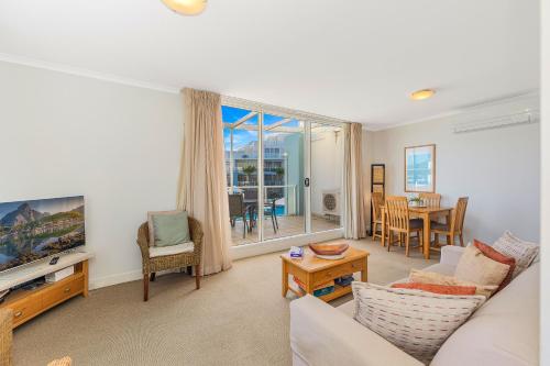 a living room with a couch and a tv at Ettalong Beach Luxury Apartments in Ettalong Beach