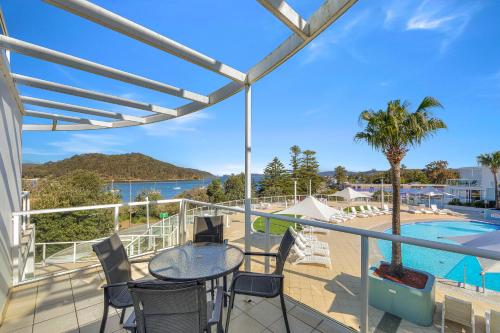 a balcony with a table and chairs and a pool at Ettalong Beach Luxury Apartments in Ettalong Beach