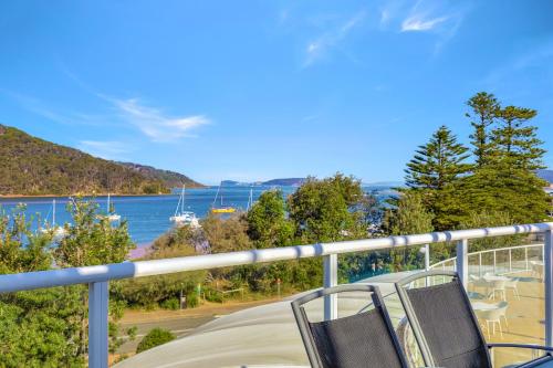 a group of chairs sitting on a balcony overlooking the water at Ettalong Beach Luxury Apartments in Ettalong Beach
