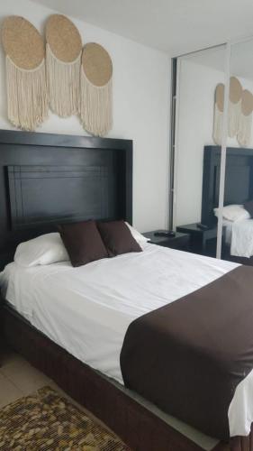 a bedroom with a large white bed with brown pillows at CASALUNA frente alberca AirAc in Atlacholoaya