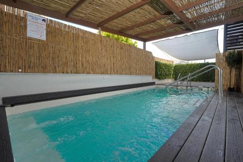 an indoor swimming pool with a wooden deck and a swimming poolvisor at לוי-קיישן מגוון דירות גן ופנטהאוזים וסוויטות נוף ברחוב הצנחנים in Tiberias