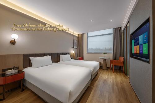 a hotel room with two beds and a flat screen tv at 上海浦东机场华美达安可酒店-免费提供24小时浦东机场班车十分钟到达候机楼出发层 in Shanghai