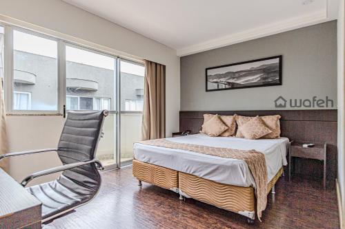 une chambre d'hôtel avec un lit et une chaise dans l'établissement San Diego Suites Pampulha - Flats Particular, à Belo Horizonte