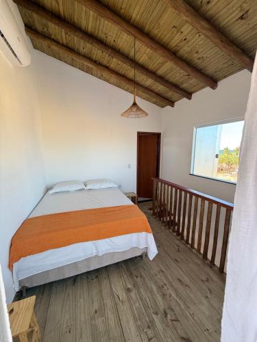 Un dormitorio con una cama y suelo de madera. en Vila Viver Caraíva, en Caraíva