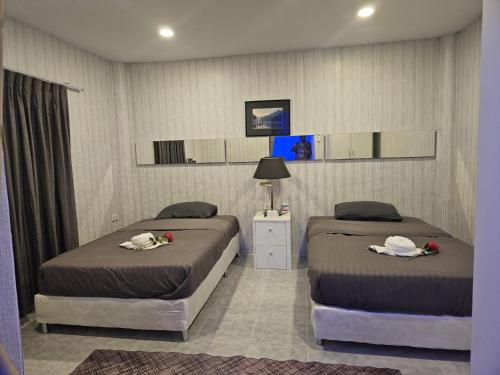 two beds in a hotel room with towels on them at บ้านพักอู้ฟู่ in Na Jomtien