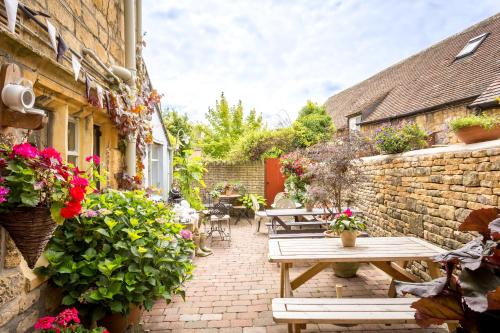 a patio with tables and flowers on a brick building at Badgers Hall in Chipping Campden
