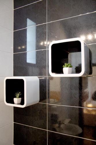 two windows on a tiled wall with two potted plants at Rooms Fitea in Osijek