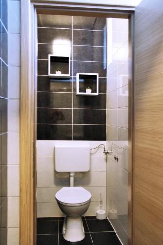 a bathroom with a toilet and two pictures on the wall at Rooms Fitea in Osijek