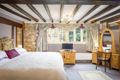 a bedroom with a large bed and a television at Badgers Hall in Chipping Campden